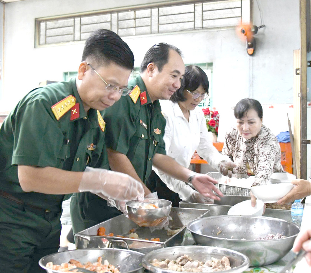 Đại tá Nguyễn Thanh Phong – Chính ủy Bộ Chỉ huy Quân sự tỉnh và Thượng tá Ngô Khánh – Phó Chính ủy Bộ Chỉ huy Quân sự tỉnh chia phần ăn cho các em
