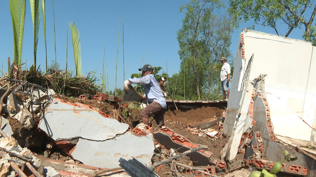 Người dân thu dọn gạch đá tại phần nền móng căn nhà bị sạt lở, nhiều mảng tường và gạch vỡ ngổn ngang sau khi nhà đổ sập