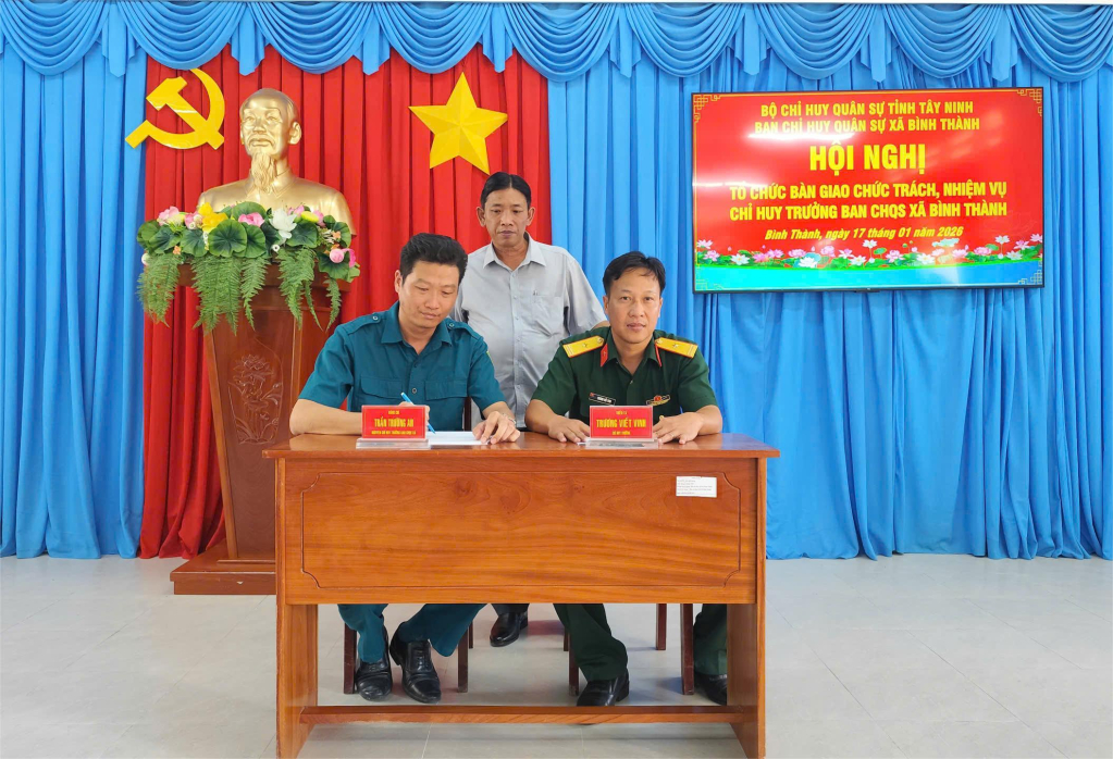 Đồng chí Trần Trường An (bên trái) bàn giao chức trách, nhiệm vụ Chỉ huy trưởng Ban Chỉ huy Quân sự xã cho Thiếu tá Trương Viết Vinh dưới sự chứng kiến của lãnh đạo địa phương.