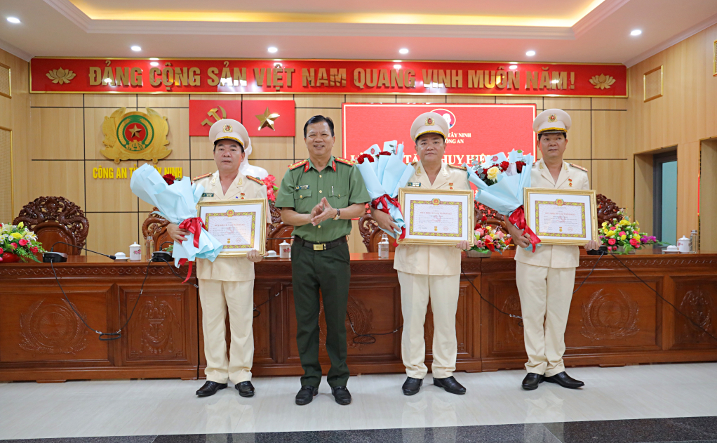 Đại tá Phan Văn Triều - Phó Bí thư Đảng ủy, Phó Giám đốc Công an tỉnh trao quyết định và tặng hoa chúc mừng 3 đồng chí