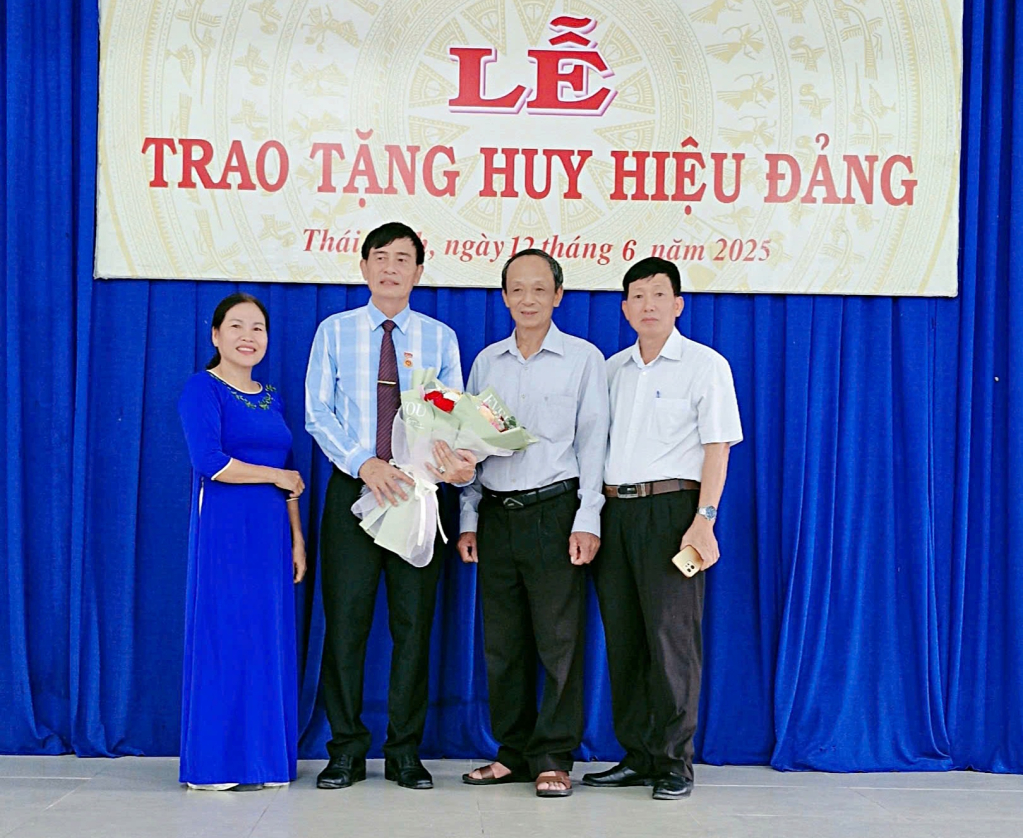 Ông Nguyễn Kim Long nhận hoa chúc mừng trong lễ trao tặng Huy hiệu Đảng