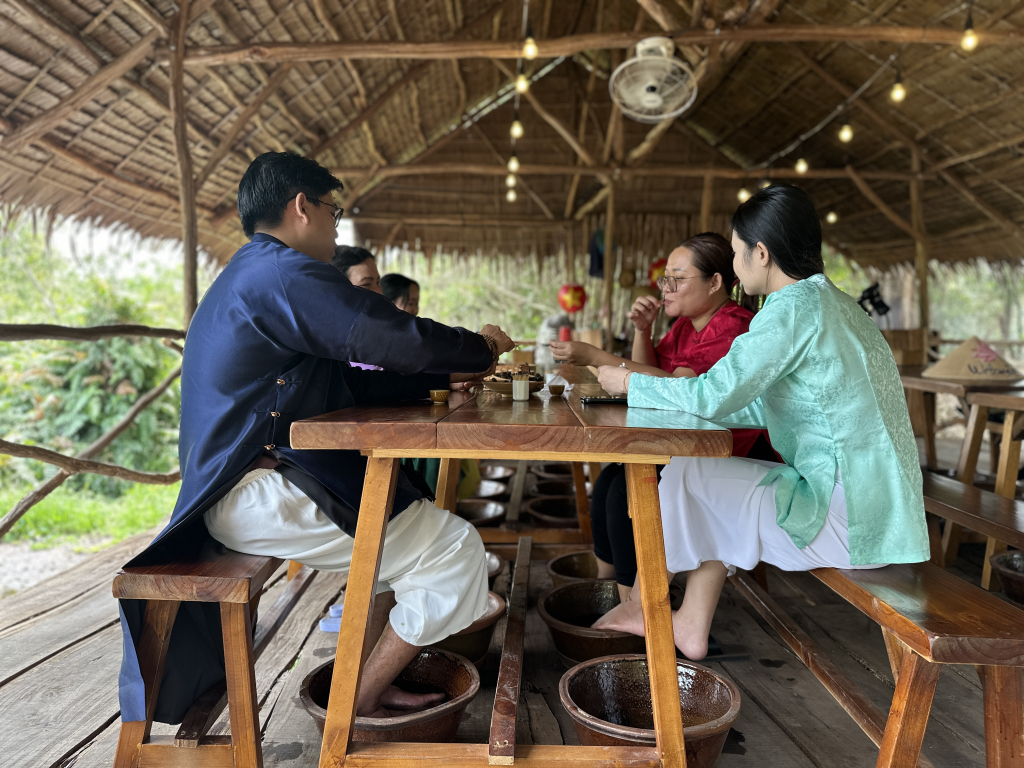 Du khách thích thú với trải nghiệm vừa ngâm chân bằng lá tràm thư giãn, vừa thưởng thức món ốc đắng đặc sản đậm hương vị miền sông nước.