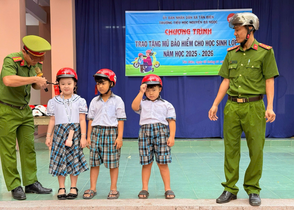 Cán bộ hướng dẫn các em học sinh đội mũ bảo hiểm đúng cách
