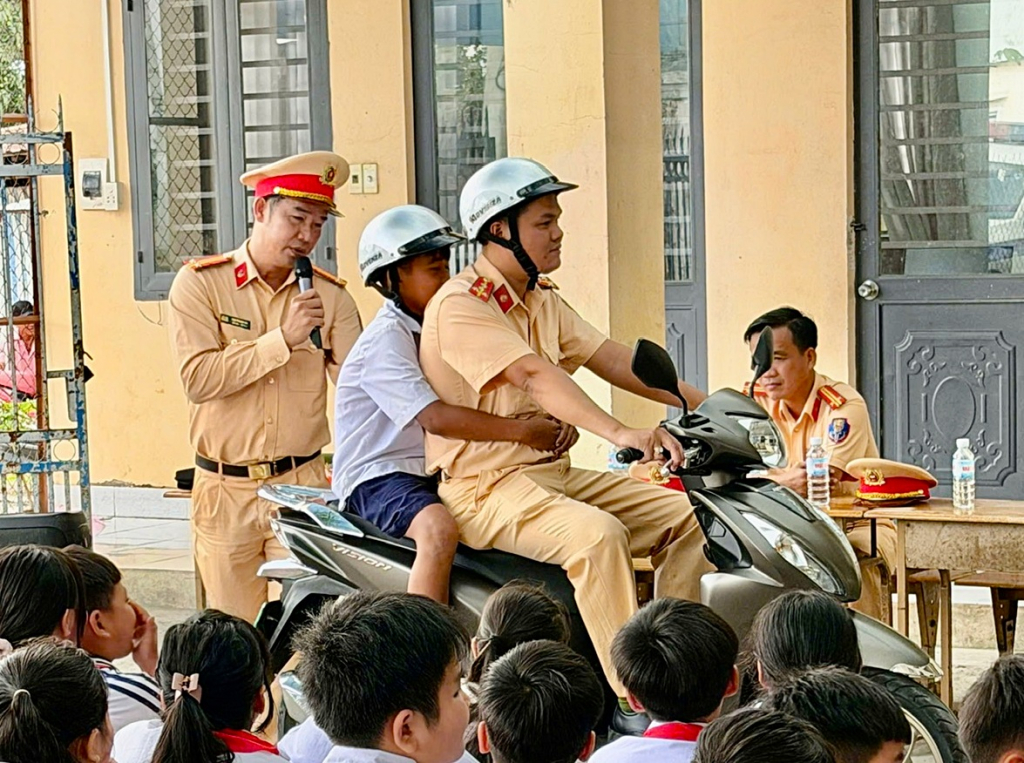 Cán bộ hướng dẫn học sinh cách ngồi sau xe của ba mẹ bảo đảm an toàn